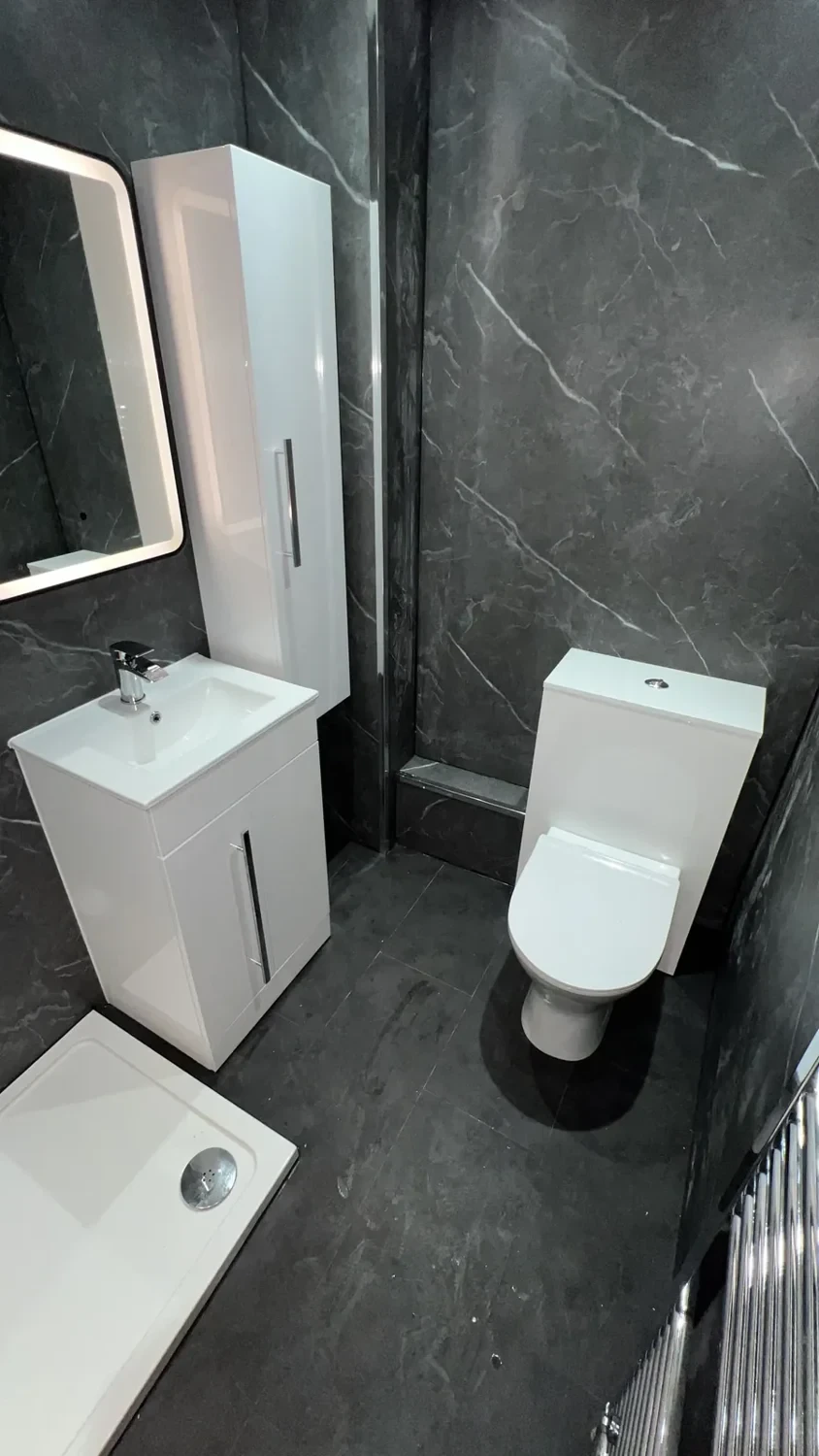 Dark marble-effect shower room with white vanity and tall storage