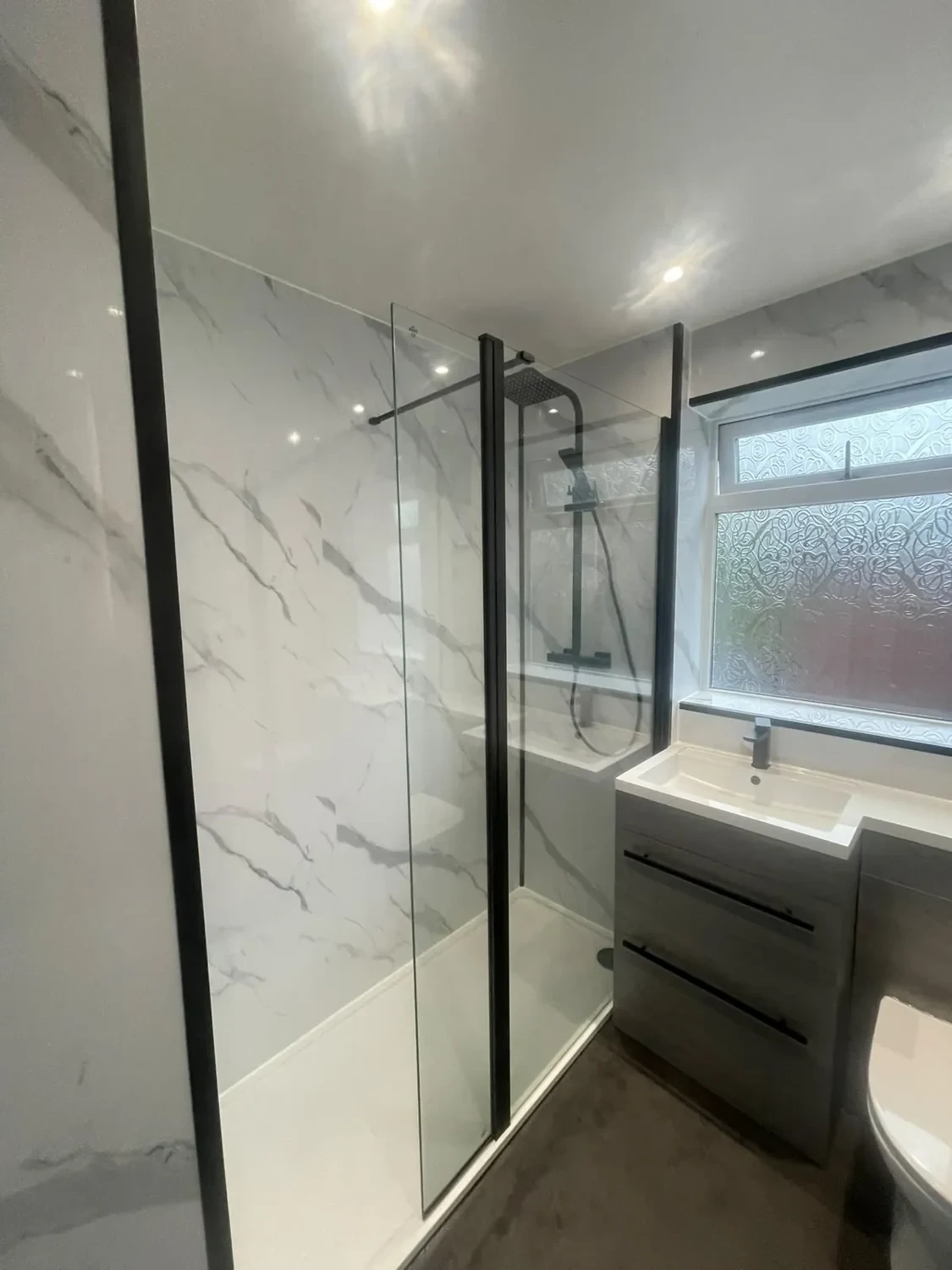 Walk-in shower beside a grey drawer vanity